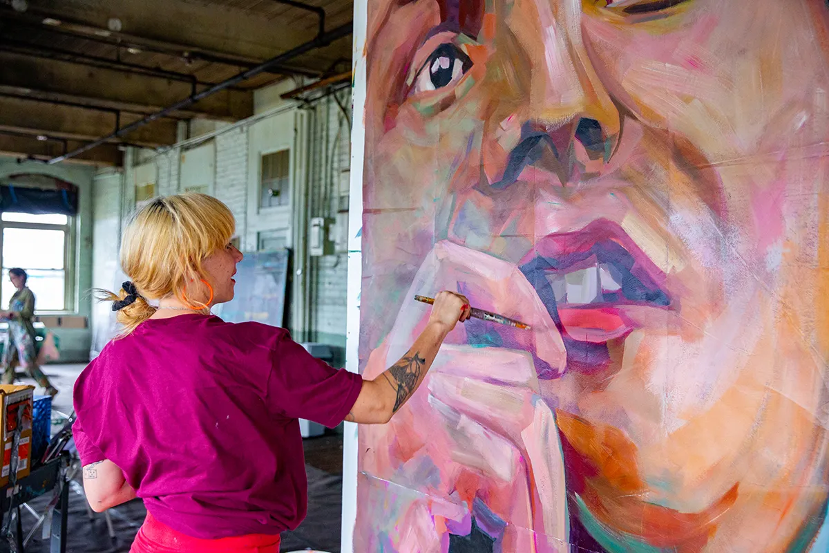 Artista pintando una sección de un mural como parte de Fresh Paint Springfield. Foto: Lauren Miller.